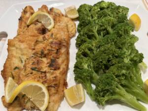 fried fish with lemons next to broccoli