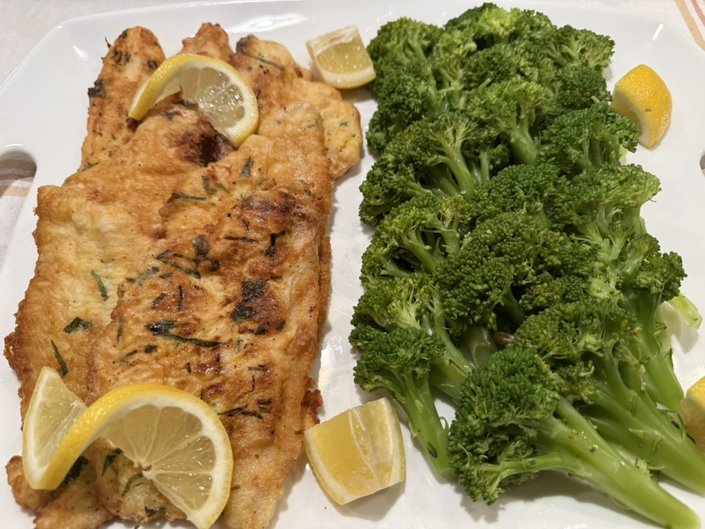 fried fish with lemons next to broccoli